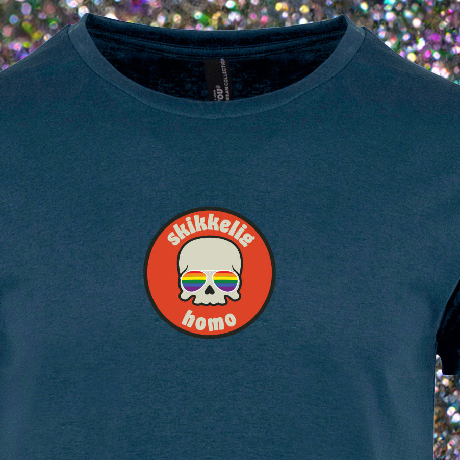 Hvit unisex T‑skjorte med trykket ‘Skikkelig Homo’ i sirkel – hodeskalle med regnbue-briller i midten, rund hals og enkel stil.